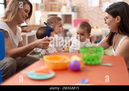 Les enseignants et les élèves d'âge préscolaire jouant avec des jouets sur la table de la maternelle Banque D'Images