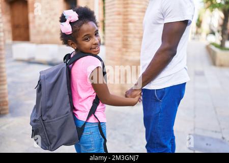 Père et fille souriant confiant marchant avec les mains ensemble à l'école Banque D'Images