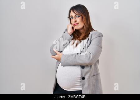 Femme enceinte d'affaires debout sur fond blanc pensant fatigué et ennuyé avec des problèmes de dépression avec les bras croisés. Banque D'Images