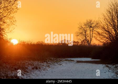 Dorney, Buckinghamshire, Royaume-Uni. 15th décembre 2022. Après un autre jour de températures inférieures à zéro, le soleil se couche sur les champs à côté de la rivière Jubilee à Dorney qui a maintenant une quantité considérable de glace de surface. La rivière Jubilee est un programme de réduction des crues qui protège Windsor, Eton et Maidenhead en cas d'inondation. Crédit : Maureen McLean/Alay Live News Banque D'Images