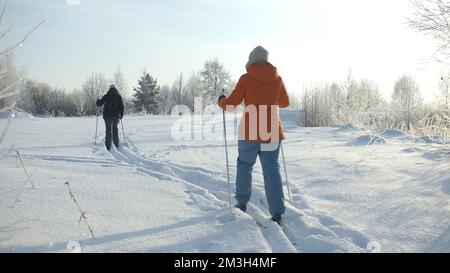 Vue arrière au ralenti des skieurs qui skient sur le sentier enneigé par une journée hivernale glacielle. Créatif. Les gens qui font de la randonnée et se déplacent dans la neige Banque D'Images