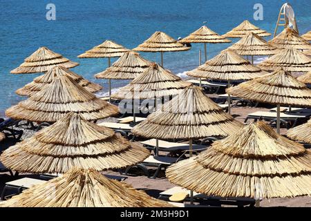 Plage avec parasols en osier et chaises longues. Vue pittoresque sur l'eau bleue, complexe tropical Banque D'Images