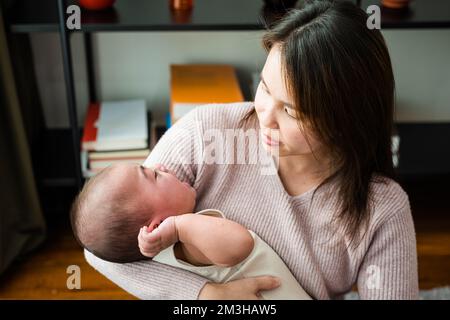 Maman asiatique tenant son petit bébé pleurant à la maison Banque D'Images