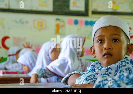 Village de Sukamanah, district de Jambe, Banten, Indonésie - 12 avril 2018 : point de mire sélectif d'un garçon étudiant élémentaire qui se fait le regard de quelque chose avec d'autres Sch Banque D'Images