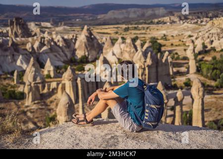 Jeune homme explorant la vallée avec des formations rocheuses et des grottes de fées près de Goreme en Cappadoce Turquie Banque D'Images