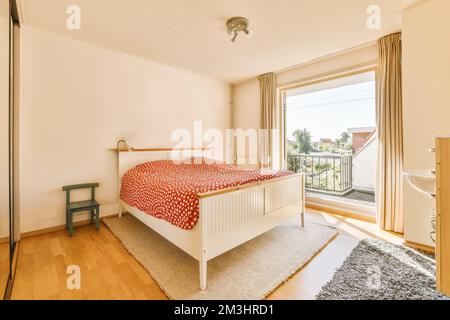 cette chambre est dotée de parquet et d''un lit blanc devant des portes vitrées coulissantes donnant sur le balcon Banque D'Images