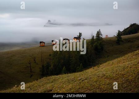 Petites maisons sur le matin brumeux entouré d'arbres sur la crête de la montagne. Petites huttes sur la crête de la colline par un jour brumeux. Banque D'Images