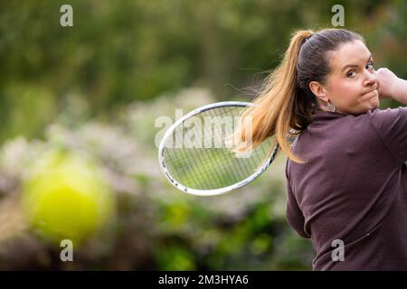 une joueuse de tennis pratiquant les mains avant et frappant des balles de tennis sur un terrain d'herbe en angleterre Banque D'Images