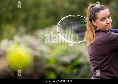 une joueuse de tennis pratiquant les mains avant et frappant des balles de tennis sur un terrain d'herbe en angleterre Banque D'Images