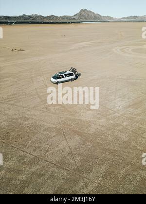 Vue aérienne d'un véhicule de loisirs autoconverti de camping-car roulant sur un lit de lac sec dans le désert du sud du nevada des États-Unis avec panneau solaire Banque D'Images