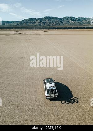 Vue aérienne d'un véhicule de loisirs autoconverti de camping-car roulant sur un lit de lac sec dans le désert du sud du nevada des États-Unis avec panneau solaire Banque D'Images