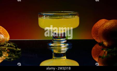 Gros plan de la boisson pétillante aux agrumes d'orange dans le verre à cocktail au ralenti. Clip d'origine. Préparation du cocktail au bar, comptoir de bar décoré avec Banque D'Images