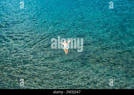 Dominique, Roseau - 12 novembre 2022: Vue de dessus d'un homme flottant dans l'eau tropicale claire, appréciant des vacances d'été Banque D'Images