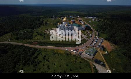 Vue aérienne d'une église blanche avec des dômes dorés. Attache. Vallée verte et village avec des arbres verts et l'église orthodoxe et le ciel bleu Banque D'Images