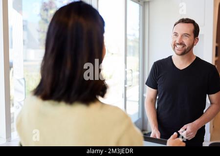 Homme mûr souriant parlant au propriétaire du café au comptoir de caisse Banque D'Images