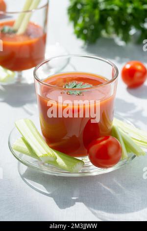 Deux verres avec jus de tomate frais, céleri, persil et tomates mûres Banque D'Images