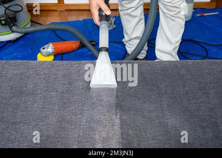 Homme utilisant un aspirateur spécial pour nettoyer les coussins du canapé. Banque D'Images