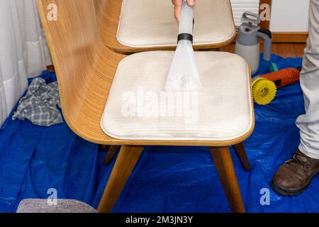 Homme utilisant un aspirateur spécial pour nettoyer la sellerie de chaise. Banque D'Images