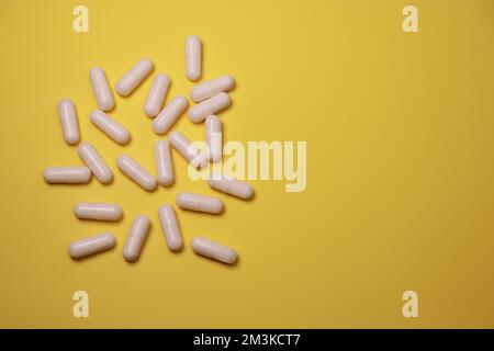gros plan des capsules de pilules blanches sur fond jaune Banque D'Images
