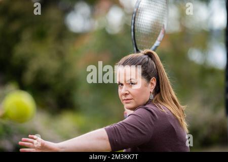 une joueuse de tennis pratiquant les mains avant et frappant des balles de tennis sur un terrain d'herbe en angleterre Banque D'Images