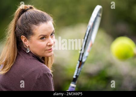 une joueuse de tennis pratiquant les mains avant et frappant des balles de tennis sur un terrain d'herbe en angleterre Banque D'Images