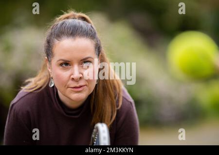 une joueuse de tennis pratiquant les mains avant et frappant des balles de tennis sur un terrain d'herbe en angleterre Banque D'Images