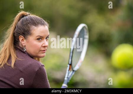 une joueuse de tennis pratiquant les mains avant et frappant des balles de tennis sur un terrain d'herbe en angleterre Banque D'Images