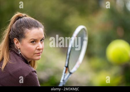 une joueuse de tennis pratiquant les mains avant et frappant des balles de tennis sur un terrain d'herbe en angleterre Banque D'Images