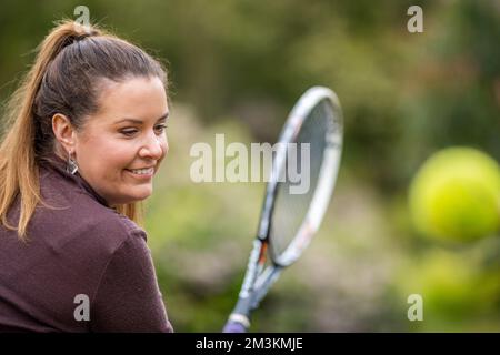 une joueuse de tennis pratiquant les mains avant et frappant des balles de tennis sur un terrain d'herbe en angleterre Banque D'Images