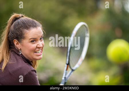 une joueuse de tennis pratiquant les mains avant et frappant des balles de tennis sur un terrain d'herbe en angleterre Banque D'Images