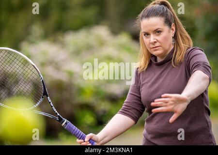 une joueuse de tennis pratiquant les mains avant et frappant des balles de tennis sur un terrain d'herbe en angleterre Banque D'Images