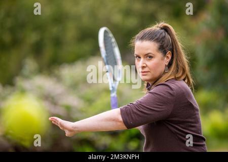 une joueuse de tennis pratiquant les mains avant et frappant des balles de tennis sur un terrain d'herbe en angleterre Banque D'Images