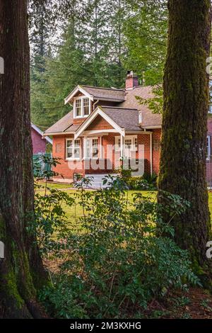 Belle maison familiale en brique rouge avec herbe verte et grands arbres. Grande maison avec véranda entourée par une belle nature. Personne. mise au point sélective, tre Banque D'Images