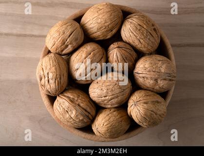 Bouquet de noix entières en coquille dans un bol en bois, vue de dessus Banque D'Images