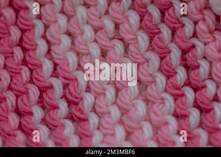 Toile de fond de texture macro-abstraite délocalisée d'un tissu tricoté à la main de couleur rose et blanche dans un motif de couture de jarretière Banque D'Images
