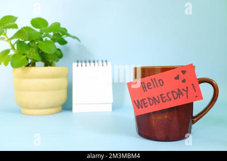 Concept de bienvenue, bonjour et Happy Wednesday. Mise au point sélective d'une tasse à café avec note en papier rouge et message écrit. Banque D'Images