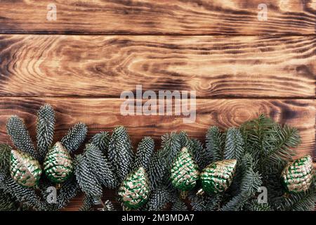 Branches vertes d'un arbre de Noël avec des décorations sous forme de cônes verts sur fond de bois avec un lieu pour le texte. Vue de dessus Banque D'Images