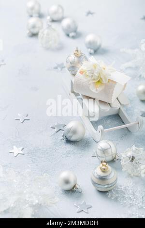 Décorations de Noël, boules et petite boîte cadeau sur traîneau en argent et blanc neige Banque D'Images