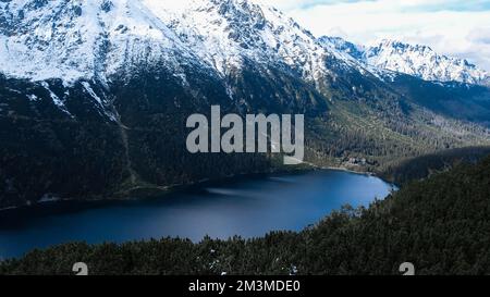 Czarny Staw Pod Rysamy ou lac Black Pond près de la cabane de montagne Morskie Oko Snowy dans les montagnes polonaises de Tatry, vue sur les drones, Zakopane, Pologne. Vue aérienne prise de magnifiques collines verdoyantes et montagnes dans des nuages sombres et reflet sur le lac Morskie Oko. Destination touristique de voyage Banque D'Images