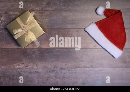 Fond horizontal de Noël. table en bois avec texture. chapeau du père noël et cadeau du nouvel an dans une belle boîte Banque D'Images