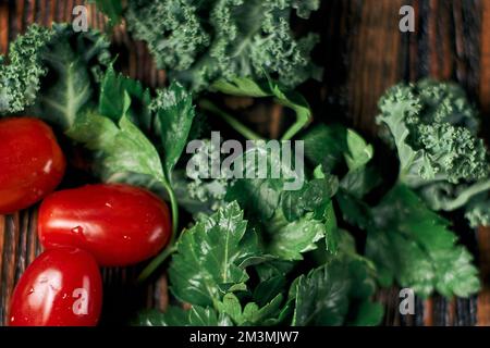 tomates fraîches et brins de persil sur une table en bois. Banque D'Images