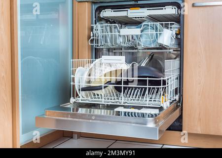 Lave-vaisselle moderne ouvert avec vaisselle en désordre dans la cuisine, lave-vaisselle intégré Banque D'Images