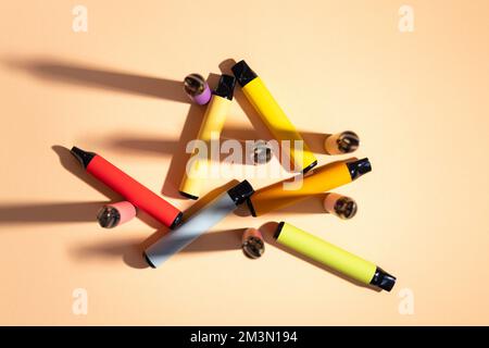 Cigarettes électroniques colorées jetables avec une solution saline de nicotine. Systèmes à dosettes. Dispositifs pour cesser de fumer. Bleu, rouge, jaune, rose. Concept de fumée alternative Banque D'Images