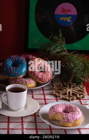 des beignets photo et une tasse de café sur une table recouverte d'une nappe rouge et blanche Banque D'Images