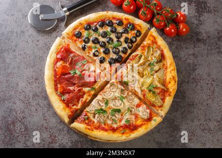 Pizza maison quatre saisons avec tomates, mozzarella, champignons, artichauts, jambon et olives en gros plan sur la table. Vue horizontale du dessus Banque D'Images