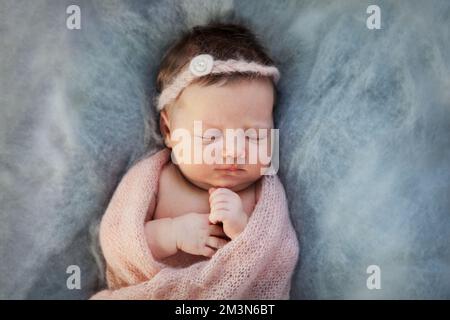 Bébé fille dormant de nouveau-né en tricot de tissu écossais rose sur fond bleu doux Banque D'Images