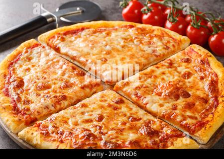 Pizza New-yorkaise fraîchement cuite au fromage mozzarella fondu et sauce tomate sur une table en bois. Horizontale Banque D'Images