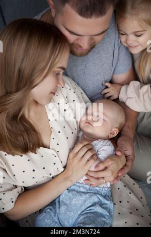 Gros plan de la famille avec deux enfants regardant le nouveau-né dormir bébé dans les bras de maman Banque D'Images