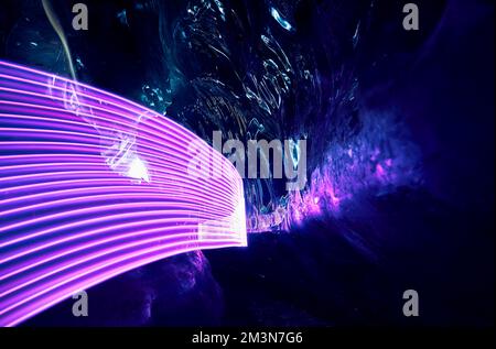 Paysage d'une incroyable grotte de glace glaciaire avec lumières à DEL pourpres à l'intérieur de la paroi de glace profonde dans le glacier de montagne d'hiver au Kazakhstan Banque D'Images