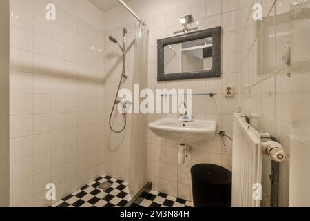 Toilettes et cabine de douche à chasse d'eau avec cloison et rideau de carreaux situés près du lavabo et du miroir dans les toilettes à la maison Banque D'Images